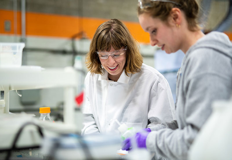 Two people in lab with goggles and purple rubber gloves